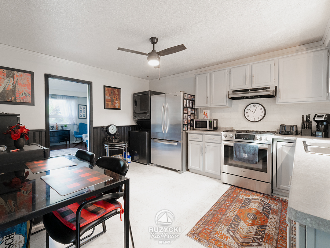 137-wellington-street-port-colborne_45 eat-in kitchen with white cabinetry and stacked top-loader washer & dryer