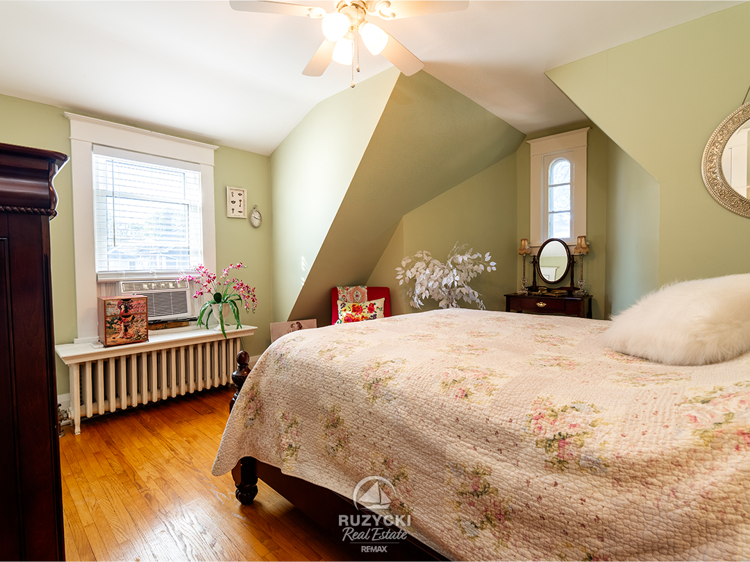 344-clarence-street-port-colborne_45 primary bedroom with sage green walls and hardwood floors